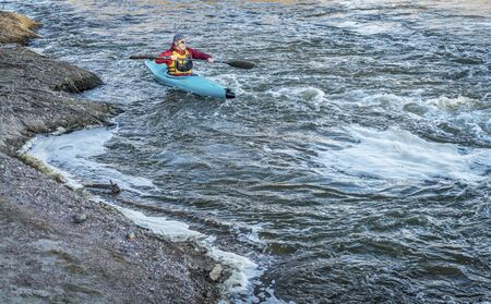 male kayaker is paddling upstream of turbulent river with a fast flowの写真素材