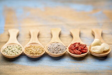 superfood (hemp seeds, golden flax seeds, chai seeds, goji berry, macadamaia nuts) on wooden spoons - abstract with a shallow depth of fieldの写真素材