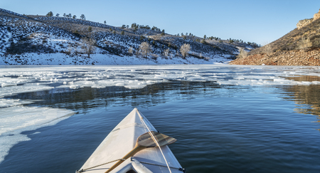 winter canoe paddling - boat bow and partially frozen lake - Horsetooth Reservoir near Fort Collins in Coloradoの写真素材