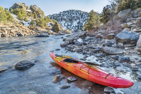 whitewater kayak with a paddle on a river shore  - Arkansas River, Colorado in winter sceneryの写真素材