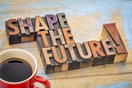 Shape the future - motivational phrase in vintage letterpress wood type blocks stained by color inksの写真素材
