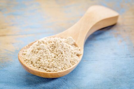 maca root  powder on wooden spoon against blue painted grunge woodの写真素材