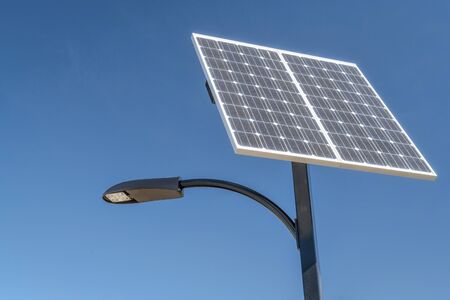 street lamp with a solar panel against blue skyの写真素材