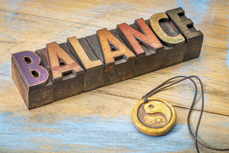 balance word in vintage letterpress wood type with ying and yang symbol pendantの写真素材