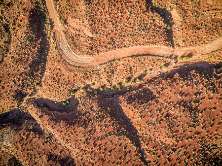 aerial view of a desert with a 4wd road and coarse vegetation near Moab, Utah - sunrise scenery with long shadowsの写真素材
