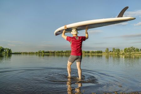 launching stand up paddleboard on a calm  lake in northern Colorado with an early summer sceneryの写真素材