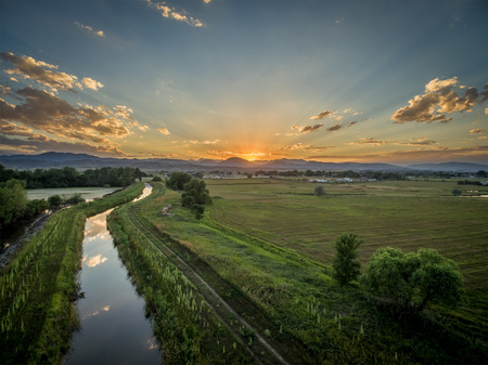 sunset over Rocky Mountains and foothills with an irrigation ditch - aerial view, northern Colorado near Lovelandの写真素材
