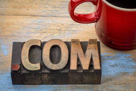 dot com business internet domain - text in vintage letterpress wood type blocks with a cup of coffee