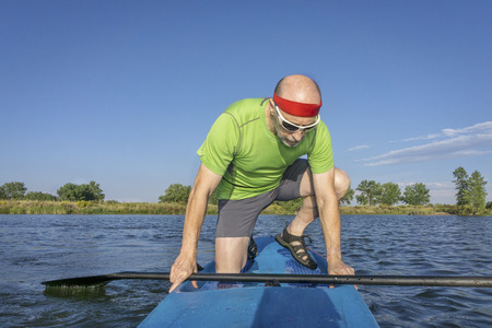 muscular, senior male paddler on a stand up paddleboard on a lake in Coloradoの写真素材