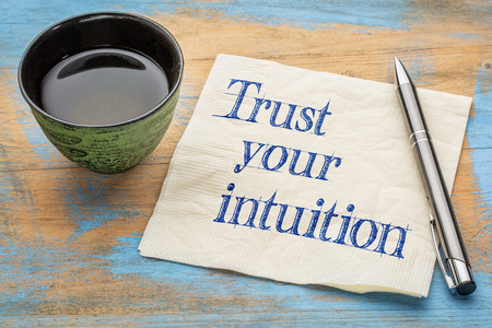 Trust your intuition reminder - handwriting on a napkin with a cup of teaの写真素材