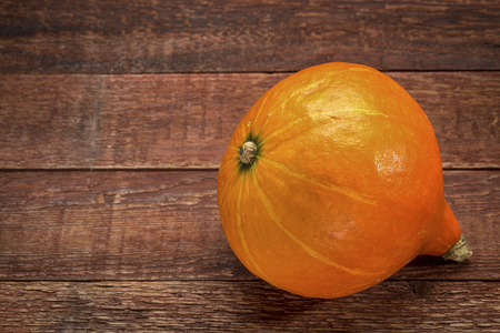 red kuri winter squash against rustic barn woodの写真素材