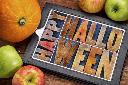 Happy Halloween greeting card -  text in vintage grunge wood type printing blocks on a digital tablet with a pumpkin and apples