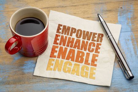 motivational leadership, coaching or business concept - empower, enhance, enable and engage  word abstract on a napkin with a cup of coffeeの写真素材