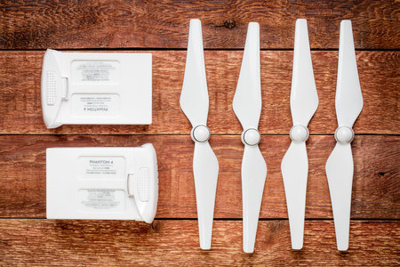 FORT COLLINS, CO, USA - JANUARY 1, 2017:  Smart flight batteries and a set of propellers for DJI Phantom 4 pro quadcopter drone on a rustic wooden table.のeditorial素材
