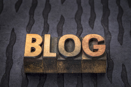 blog word - text in vintage letterpress wood type printing blocks against black lokta paperの写真素材