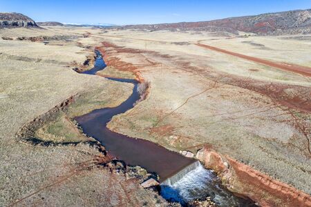 northern Colorado foothills aerial view with a creek, dam and cattle walk paths