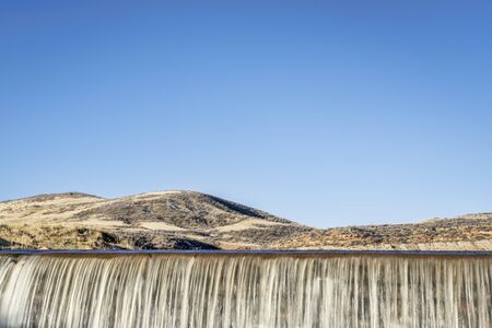 water cascading over a dam in Colorado foothills against blue skyの写真素材