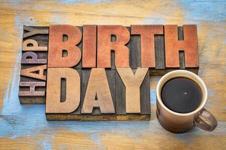 Happy Birthday greeting card - word abstract in vintage letterpress wood type blocks against grunge wooden background with a cup of coffeeの写真素材
