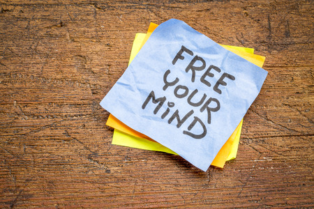 free your mind advice or reminder - handwriting on a sticky note against rustic grunge wood boardの写真素材