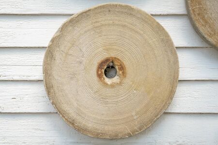 vintage grinding stone hanging on a house wallの写真素材