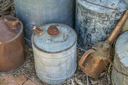 vintage rusty oil cans of different sizes neglected in a farm workshopの写真素材