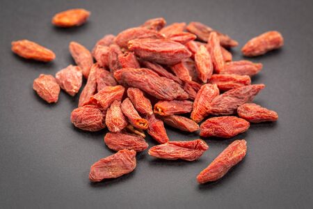 a heap of dried Tibetan goji berries (wolfberry) on a dark ceramic  surfaceの写真素材