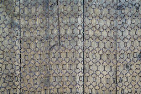 background and texture of vintage chain mesh against weathered woodの写真素材