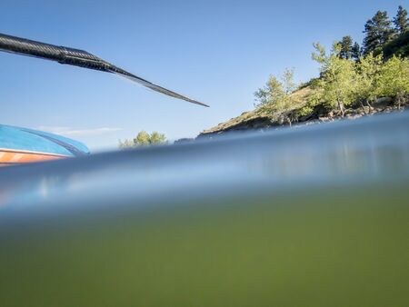 Stand up paddling on a mountain lake, partially underwater abstract shot