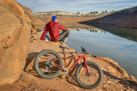 a male biker resting on a shore of Horsetooth Reservoir after rider a fat bikeの写真素材