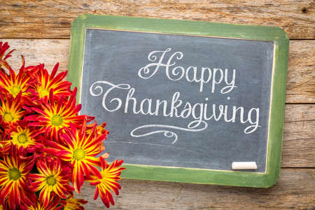 Happy Thanksgiving greeting card - white chalk text on a  vintage slate blackboard with a pot of mumsの写真素材