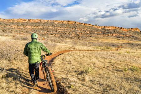 Male cyclist with a fat bike on a trail in Colorado foothills (Lory State Park near Fort Collins), a typical cold, but snowless winter afternoonの写真素材