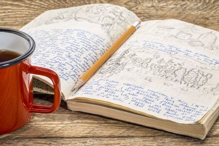Kayak expedition journal with a cup of tea on a rustic picnic table- handwriting and drawing in...