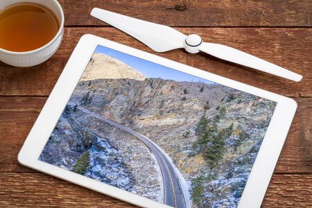 Poudre River canyon with a scenic road in winter scenery, reviewing an aerial image on a digital...