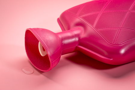 red watter rubber bottle on pink background - heat and cold therapyの写真素材