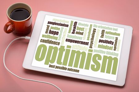 optimism word cloud on a digital tablet with a cup of coffeeの写真素材