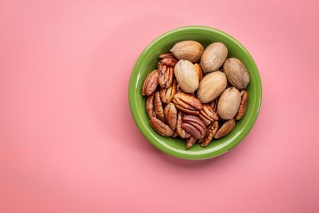 pecan nuts in a ceramic bowl against pink background with a copy spaceの写真素材