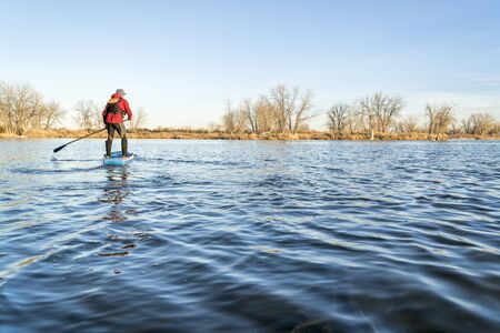 stand up paddling on a lake in Colorado, winter or early spring sceneryの写真素材