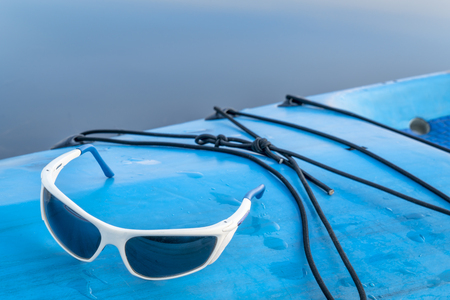 sport sunglasses on a wet deck of stand up paddleboardの写真素材