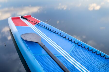 Deck of a racing stand up paddleboard with a paddle and sefety leash.の写真素材