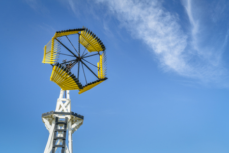 Antique windmill for water pumping in Amercian prairie against blue skyの写真素材