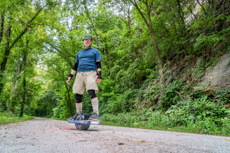 Rocheport, MO, USA - July 29, 2-18: A senior man is riding oneweel electric skateboard on Katy Trail...