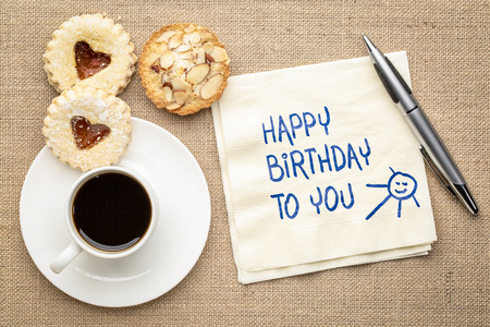 Happy Birthday to you greeting card - handwriting on a napkin with a cup of coffee and cookiesの写真素材