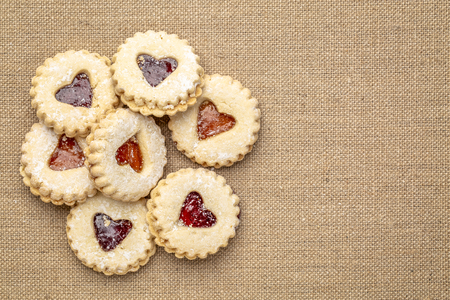 a pile of jam heart biscuits on burlap canvas with a copy spaceの写真素材