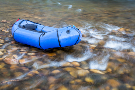 a blue pacraft (one-person light raft used for expedition or adventure racing) on a shallow, rocky t a shallow riverの写真素材
