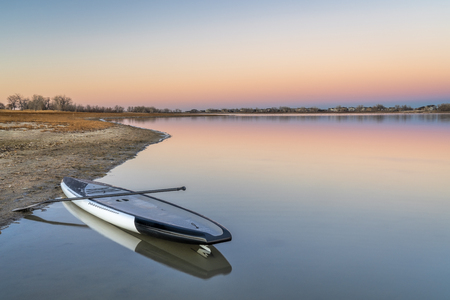 dusk over lake in Colorado with a stand up paddleboard on a beachの写真素材