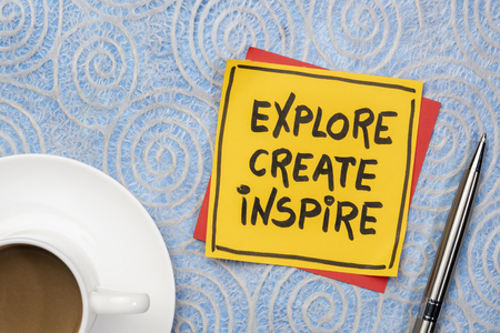 explore, create, inspire- inspirational reminder on sticky note with a cup of coffee against lace paper with a spiral patternの写真素材