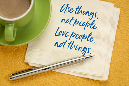 Use things, not people. Love people, not things. Inspiraitonal handwriting on a napkin with a cup of coffee.の写真素材