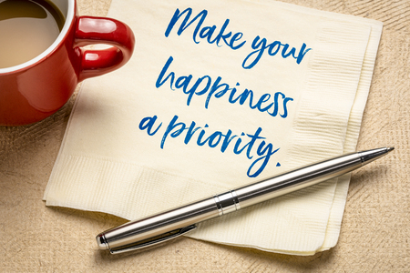 Make your happiness a priority - handwriting on a napkin with a cup of coffeeの写真素材