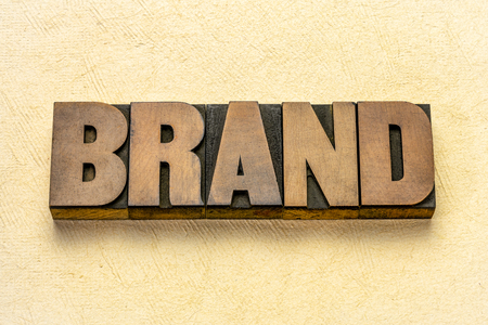 brand word in vintage letterpress wood type against textured bark paper backgroundの写真素材