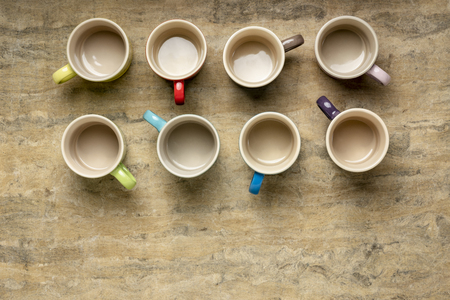 collection of empty colorful stoneware coffee cups against textured handmade bark paper with a copy spaceの写真素材